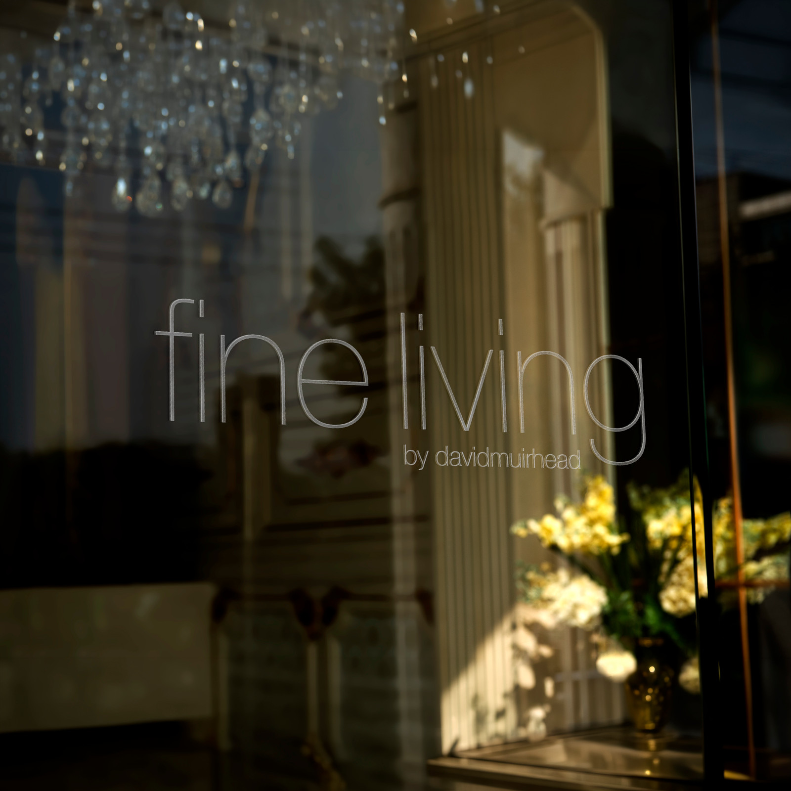 The Fine Living by David Muirhead wordmark etched across the showroom window at dusk.
