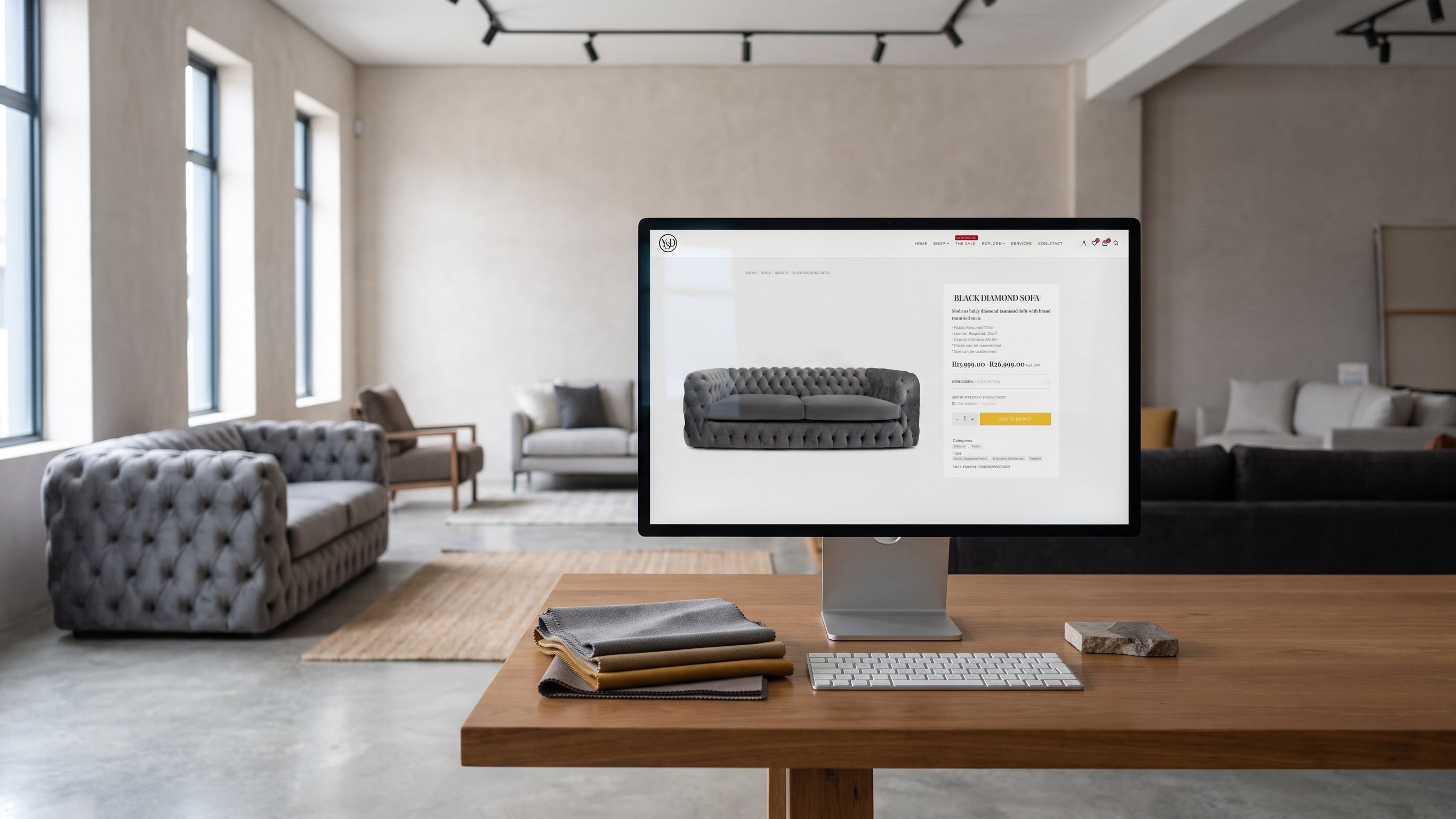 A desktop display on a timber consultation table in a furniture showroom, showing the Black Diamond Sofa page. Grey buttoned sofas and armchairs stand on a polished concrete floor behind it, with tall windows along the far wall.
